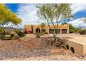 Single story home featuring desert landscaping, mature trees, and an attached two-car garage at 5978 E Chuckwalla Trl, Cave Creek, AZ 85331
