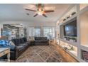 Open-concept living room with a spacious seating area, ceiling fan, and built-in entertainment center at 10850 W Bronco Trl, Peoria, AZ 85383