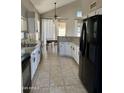 Well-lit kitchen with white cabinets, granite countertops, tile flooring, and modern black appliances at 11001 Clear Water --, Goodyear, AZ 85338