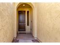 Arched entry featuring a solid wood door with textured walls and stylish stone accents at 18417 W Elm St, Goodyear, AZ 85395