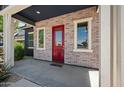 Inviting front porch featuring a red brick accent wall and a vibrant red front door at 23451 S 228Th St, Queen Creek, AZ 85142