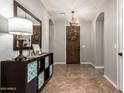 Welcoming foyer with a decorative mirror, tile flooring, and an ornate wood entry door at 233 W Sweet Shrub Ave, San Tan Valley, AZ 85140