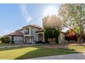 Two-story home with a tile roof and balcony, surrounded by a green lawn and mature trees at 2438 N Forest Cir, Mesa, AZ 85203