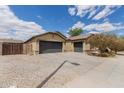 Tan single story home featuring a spacious driveway, two-car garage, and xeriscaped yard, under a partly cloudy sky at 25212 W Maldonado Dr, Buckeye, AZ 85326