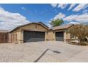 Tan single story home featuring a spacious driveway, two-car garage, and xeriscaped yard, under a partly cloudy sky at 25212 W Maldonado Dr, Buckeye, AZ 85326