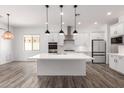 Spacious open kitchen featuring an island with seating, white cabinets, stainless steel appliances, and modern pendant lights at 26860 N 102Nd Ln, Peoria, AZ 85383