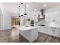 Open-concept kitchen featuring white cabinets, stainless steel hood, a large island, and pendant lighting at 26860 N 102Nd Ln, Peoria, AZ 85383