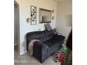 Comfortable living room with a dark gray couch, tile floors, decorative wall art and a large mirror at 3825 S 60 Dr, Phoenix, AZ 85043