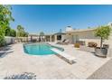 Backyard view of a refreshing pool with diving board, tiled patio, lounge chairs and well-kept landscaping at 5711 E Corrine Dr, Scottsdale, AZ 85254