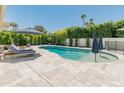 A kidney shaped pool is surrounded by lounge chairs and umbrellas and a fence for safety at 5711 E Corrine Dr, Scottsdale, AZ 85254