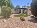 Private backyard featuring a patio, artificial turf, mature landscaping, and desert vegetation at 9406 S 47Th Pl, Phoenix, AZ 85044