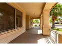 Inviting covered porch featuring views of mature landscaping, beautiful lawn and palm trees at 12428 W Vermont Ct, Litchfield Park, AZ 85340