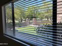 View from window with closed blinds overlooking a green lawn, trees, and a gated entrance to the community at 15225 N 100Th St # 1220, Scottsdale, AZ 85260