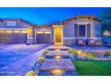 Stunning curb appeal with a brick pathway, ambient lighting, and charming front porch at 16042 W Shaw Butte Dr, Surprise, AZ 85379