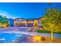 Well-lit home exterior showcasing a three-car garage and inviting front entrance at 16042 W Shaw Butte Dr, Surprise, AZ 85379