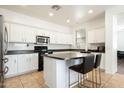 Bright kitchen featuring an island, white cabinets, and modern appliances at 17613 N 114Th Ln, Surprise, AZ 85378