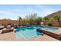 Backyard pool and spa area with stone accents, palm trees, and a seating area at 25943 N 84Th Dr, Peoria, AZ 85383