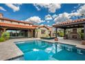 Stunning backyard with a sparkling pool, covered patio, outdoor fireplace, and lush landscaping for luxurious outdoor living at 37440 N 104Th Pl, Scottsdale, AZ 85262