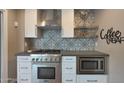 Close up of a kitchen cooktop with stainless steel appliances and a decorative backsplash at 4248 N Parkway Ave, Scottsdale, AZ 85251