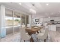 Dining room features a modern chandelier, wood table and chairs, and sliding door access to outdoor pool at 8010 W Atlantis Way, Phoenix, AZ 85043