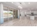 Open-concept living room with seamless access to a patio, tiled floors, modern lighting, and an adjacent kitchen at 8010 W Atlantis Way, Phoenix, AZ 85043