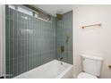 Bathroom displaying a bathtub with shower, blue-green tiling, and sleek gold fixtures at 821 E Harmony Ave, Mesa, AZ 85204