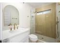 Bathroom showcasing a modern vanity, an arched mirror, gold fixtures, and a glass-enclosed shower at 821 E Harmony Ave, Mesa, AZ 85204