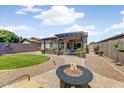 Beautiful backyard with a pergola-covered patio, lush lawn, and inviting fire pit at 913 W Leadwood Ave, Queen Creek, AZ 85140