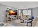 Cozy living room boasts a large television, stylish shelving, and comfortable seating arrangement with natural light at 9444 W Roma Ave, Phoenix, AZ 85037