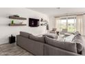 Spacious living room featuring a large gray sectional sofa and sliding glass doors to the backyard at 13228 W Buckskin Trl, Peoria, AZ 85383