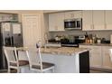 Modern kitchen features white cabinets, granite countertops, and stainless steel appliances at 16046 W Hearn Rd, Surprise, AZ 85379