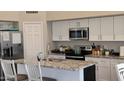 Modern kitchen features white cabinets, granite countertops, and stainless steel appliances at 16046 W Hearn Rd, Surprise, AZ 85379