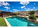 Backyard pool area featuring travertine decking, desert views, outdoor kitchen and artificial turf at 16389 W Fawn Dr, Goodyear, AZ 85338