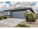 Single-Gathering home features a gray two-car garage with a paved driveway and desert landscaping at 17376 W Via De Luna Dr, Surprise, AZ 85387