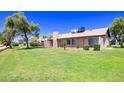 Large backyard with green grass, mature trees, a fence and a cozy patio area at 17802 N 45Th Ave, Glendale, AZ 85308