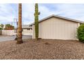 Side yard of a home with desert landscaping, palm trees, and a mature Saguaro cactus at 2001 W Surrey Ave, Phoenix, AZ 85029
