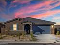Attractive single-story home with desert landscaping and a blue garage door set against a colorful sky at 20368 N 224Th Dr, Surprise, AZ 85387