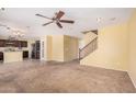 Spacious living room with carpeted floors, ceiling fan, and seamless transition to the kitchen and staircase at 22123 E Vía Del Palo --, Queen Creek, AZ 85142