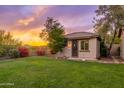 Charming backyard featuring lush green lawn, desert landscaping, wrought iron fence, and picturesque sunset views at 31900 N 127Th Ln, Peoria, AZ 85383