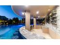 Outdoor bar overlooking custom pool featuring a swim-up bar, grotto, water slide, and multiple water features at 4281 S Iowa St, Chandler, AZ 85248