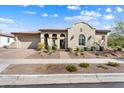 Stunning Southwestern-style home with a desert landscape, decorative arches, and a brick-paved driveway and walkway at 5033 N 205Th Gln, Buckeye, AZ 85396