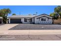 Charming one-story home showcasing a dark gray garage door, rock landscaping, and a well-maintained lawn at 6413 E Parkview Dr, Scottsdale, AZ 85257