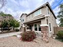 Charming two-story home featuring desert landscaping, a covered porch and stone-accented columns at 7258 W State Ave, Glendale, AZ 85303