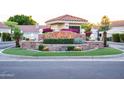 Community entrance with stone monument, mature landscaping, and well-maintained street at 8635 W Country Gables Dr, Peoria, AZ 85381