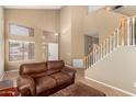 Bright living room with a soaring ceiling, staircase, large window and neutral colors at 9343 W Quail Ave, Peoria, AZ 85382
