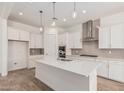 Bright kitchen with stainless steel appliances, island, white cabinets, and tile backsplash at 16494 W Creedance Blvd, Surprise, AZ 85387