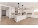 Modern kitchen with a large island, pendant lighting, and stainless steel range hood at 16550 W Creedance Blvd, Surprise, AZ 85387