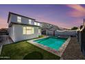 Inviting backyard featuring a sparkling pool, green turf, and string lights, perfect for outdoor entertaining at 16840 W Monroe St, Goodyear, AZ 85338