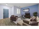 Inviting living room with wood floors, a blue accent wall, comfortable seating and lots of natural light at 20200 N Donithan Way, Maricopa, AZ 85138