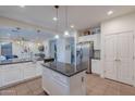 Spacious kitchen featuring stainless steel refrigerator, white cabinets, granite countertops, and eat-in island at 3901 E Packard Dr, Gilbert, AZ 85298